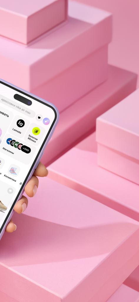 Dolyame - оплата покупок - Una mano sosteniendo un smartphone mostrando la interfaz de la aplicación de compras Dolyame con socios minoristas sobre un fondo de cajas rosas apiladas