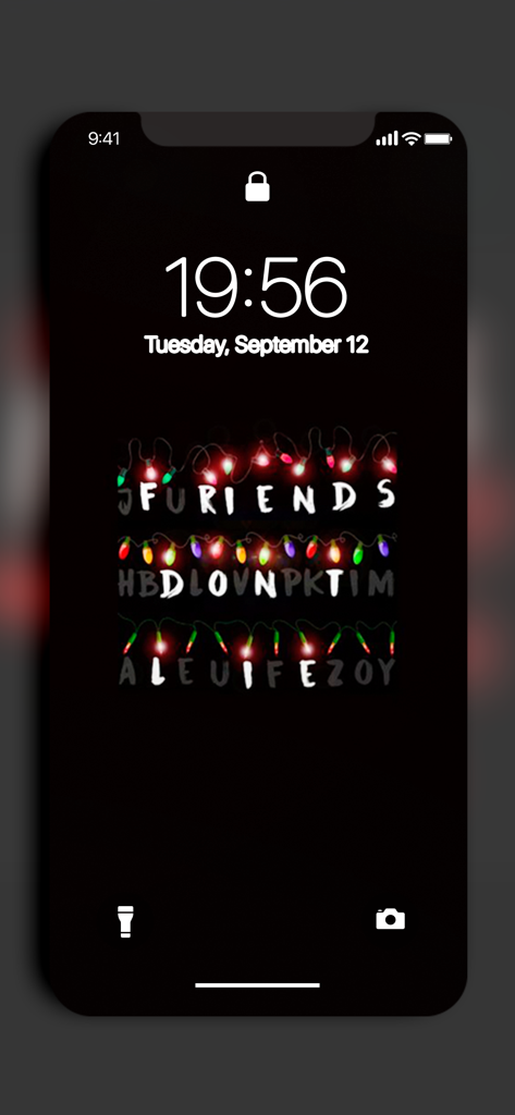 Schermata di blocco dell'iPhone che mostra uno sfondo di Stranger Things con luci di Natale che compongono la frase Friends Dont Lie.