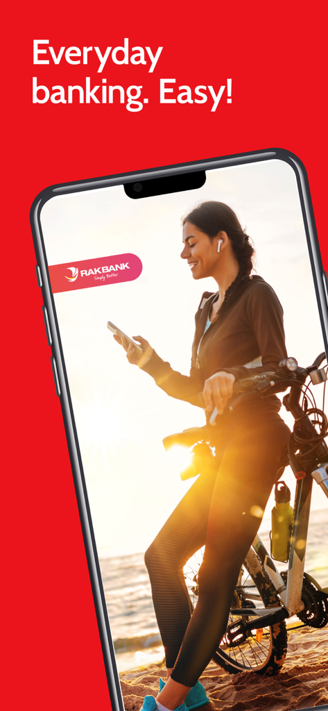 A woman with a bicycle using the RAKBANK app on her phone at the beach during sunset