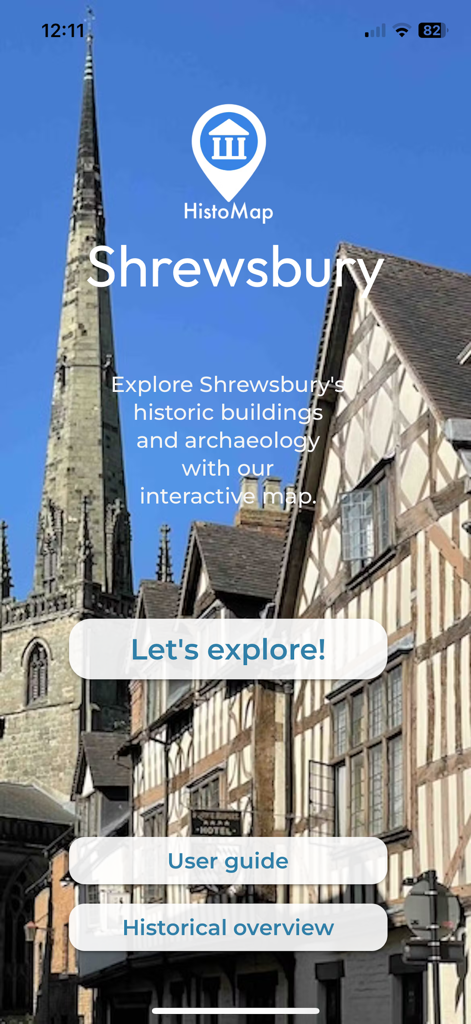 HistoMap Shrewsbury - ヒストマップ・シュルーズベリーのアプリホーム画面。歴史的な木骨造りの建物と教会の尖塔を背景にしています。