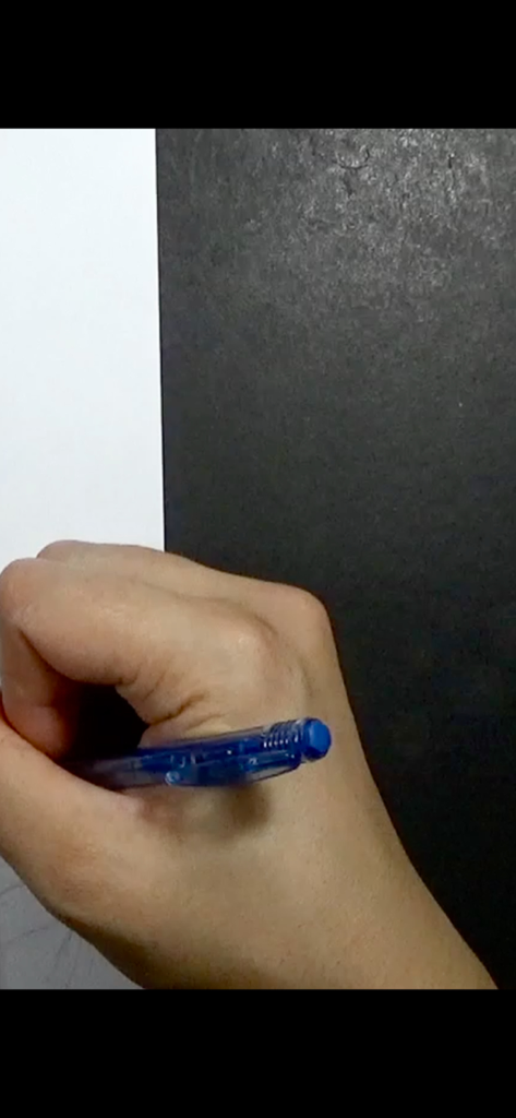 Primo piano di una mano che impugna una penna blu per disegnare su carta bianca