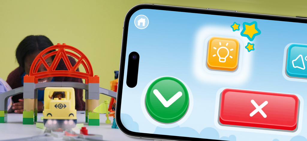 Un smartphone mostrando la interfaz de la aplicación LEGO DUPLO Trenes con botones grandes y coloridos junto a un set de trenes de juguete físico