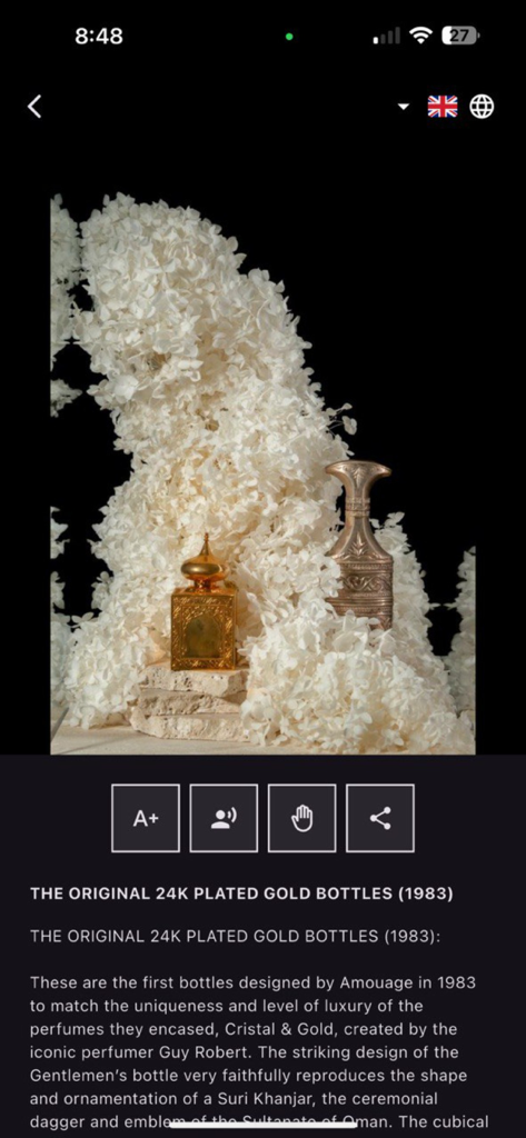 Amouage Visitors' Center - Display of the original 1983 Amouage 24K plated gold perfume bottles surrounded by white flowers.