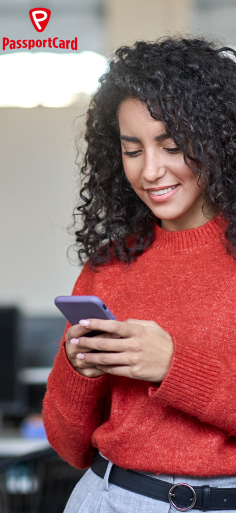 A young woman smiling while using the PassportCard Assist app on her smartphone