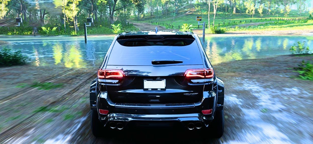 Offroad Car Simulator Games 3D - Vista trasera de un SUV negro conduciendo por un sendero todoterreno escénico con agua y árboles en un juego de simulación 3D.