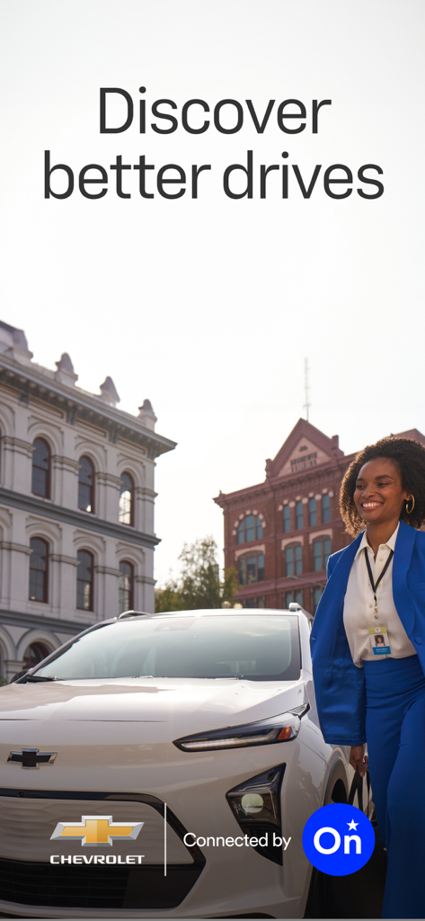 A professional woman in a blue suit walking next to a white Chevrolet vehicle in a city with the slogan Discover better drives