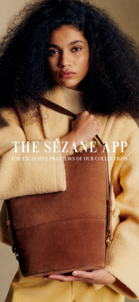 A model wearing a yellow coat and holding a brown suede bag promoting the Sezane app