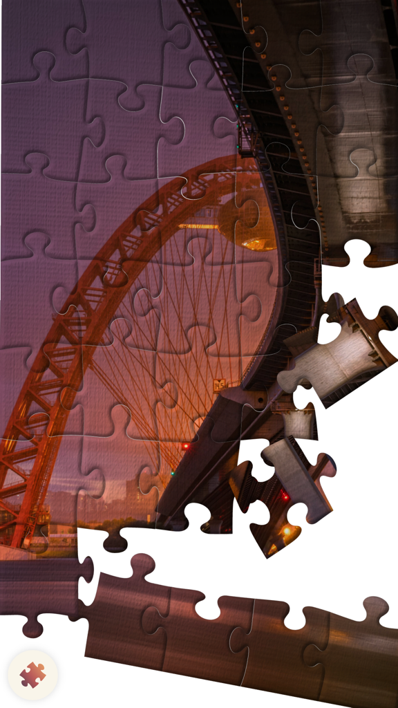Puzzle.Plus – Classic jigsaw puzzle in your hands - A digital jigsaw puzzle of a red bridge at sunset with several pieces being assembled.