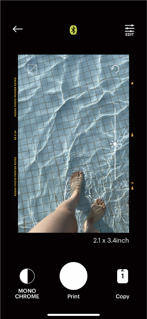 Interface of the Kodak Photo Printer app showing a pool photo being edited with a brightness slider before printing