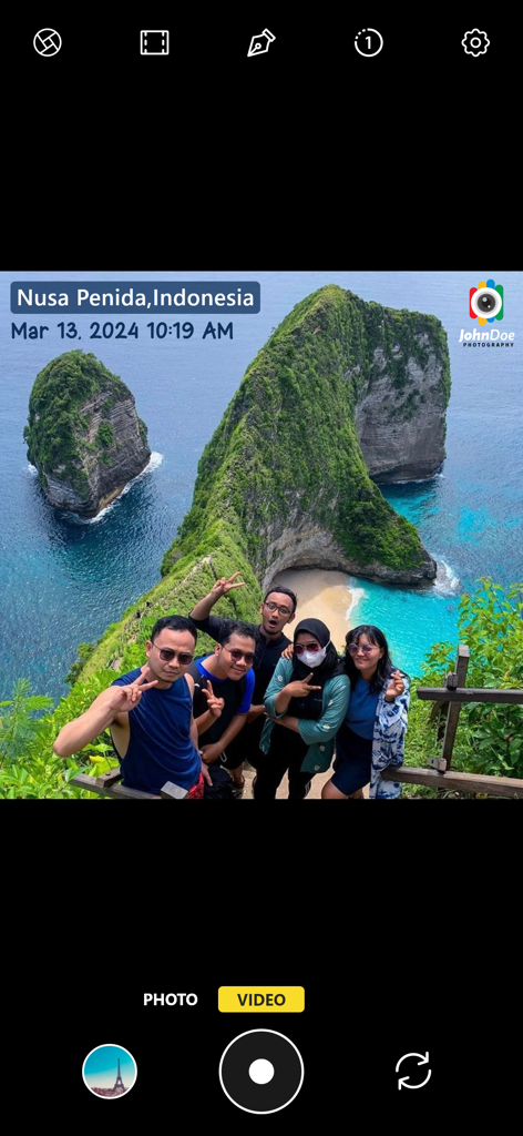 Interfaccia della fotocamera che mostra una foto di gruppo con timbri automatici di posizione, data e logo del fotografo