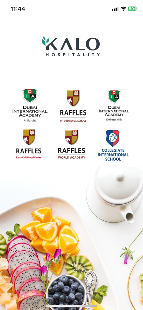 Kalo Hospitality app screen showing logos of partner schools and a platter of healthy fresh fruit.