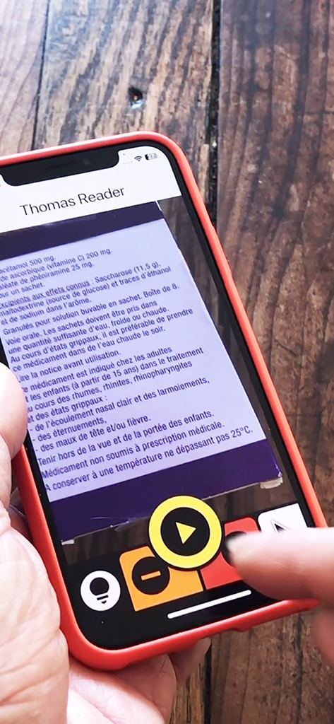Thomas Reader - A person using the Thomas Reader app on an iPhone to scan and read aloud text from a printed document