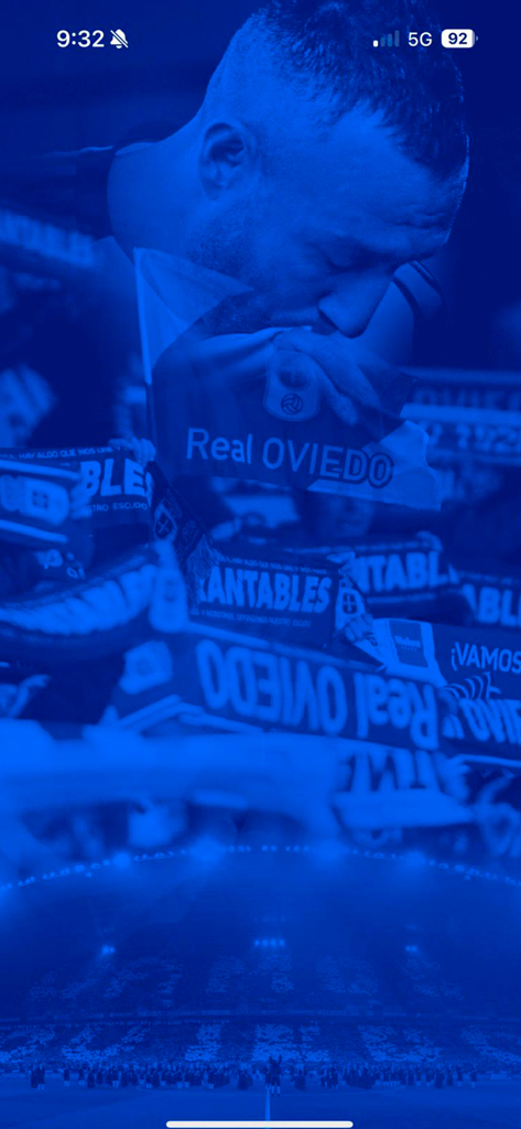 Real Oviedo - Official App - Un aficionado apasionado besando una pancarta del Real Oviedo en la pantalla de inicio de la app oficial.