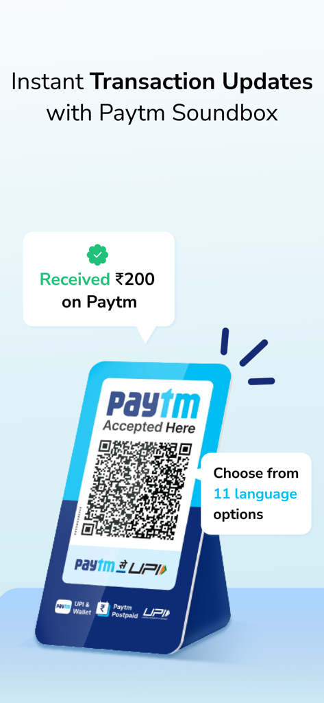 A Paytm for Business QR code stand displaying a successful transaction notification and language options