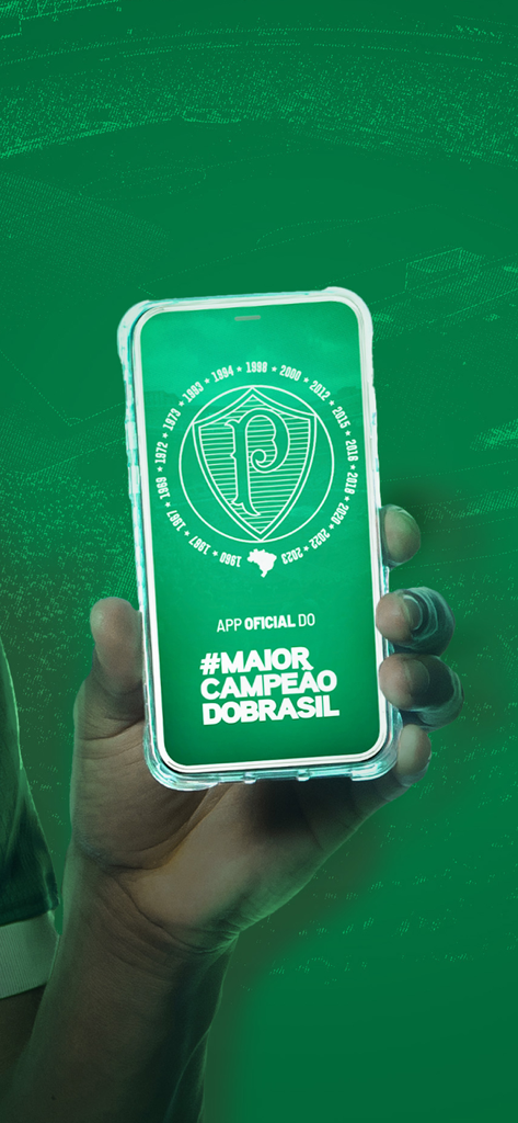 Palmeiras Oficial - A hand holding a smartphone showing the Palmeiras Oficial app logo and championship titles on a green screen.