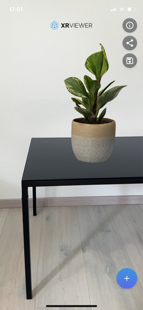 XR Viewer app displaying a 3D digital potted plant on a real black table using augmented reality
