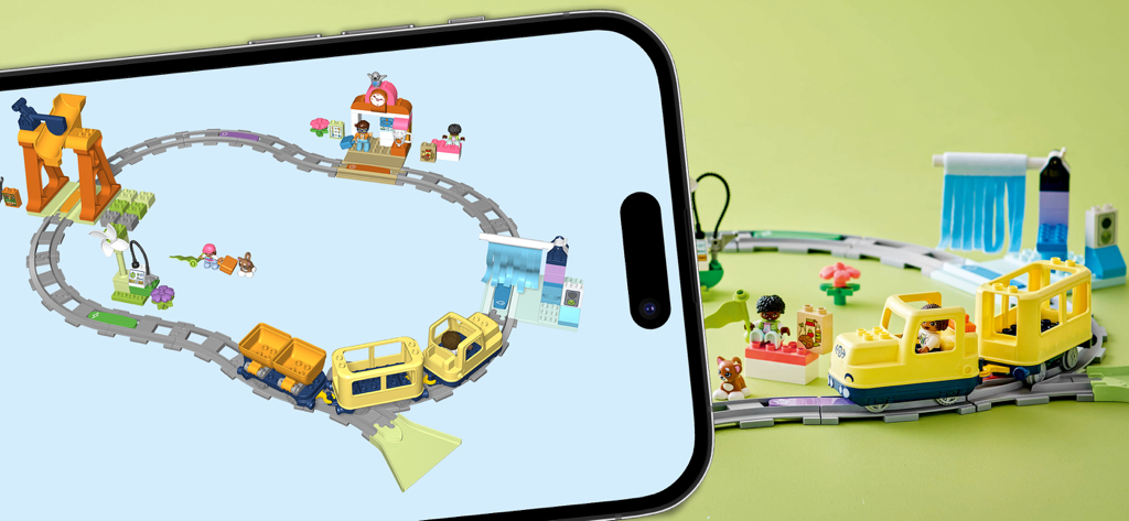 Smartphone mostrando la aplicación LEGO DUPLO Trenes junto a un set de trenes LEGO físico.