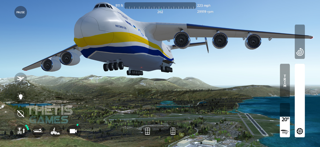 An Antonov 225 cargo plane flying over a landscape with mountains and an airport in FlyWings 2018 Flight Simulator.