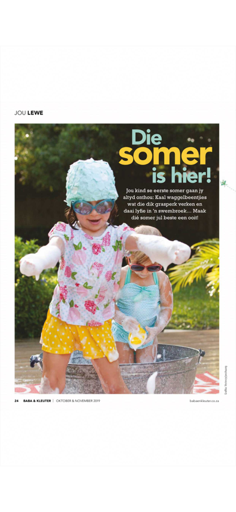 Two young children playing with soap bubbles in an outdoor tub featured in an Afrikaans parenting magazine