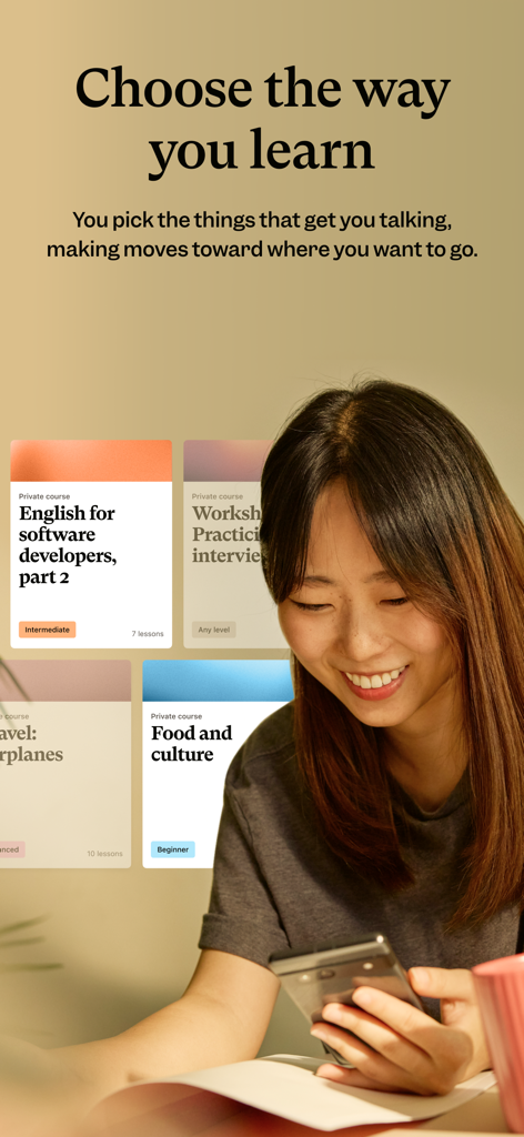 A woman smiling while looking at her phone showing personalized English courses on the Cambly app