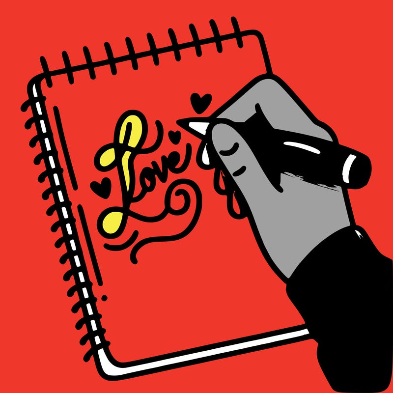 a hand writing “love” in calligraphy on a notebook