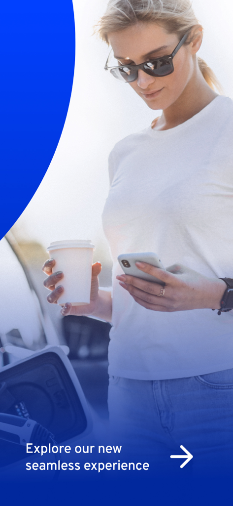 ElectricRoutes - A woman holding a coffee and checking the ElectricRoutes app while her electric vehicle is charging