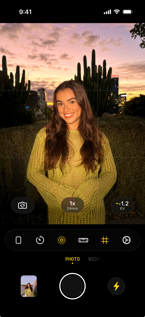 A mobile phone screenshot showing the flag7x camera interface with a woman posing for a portrait against a sunset backdrop