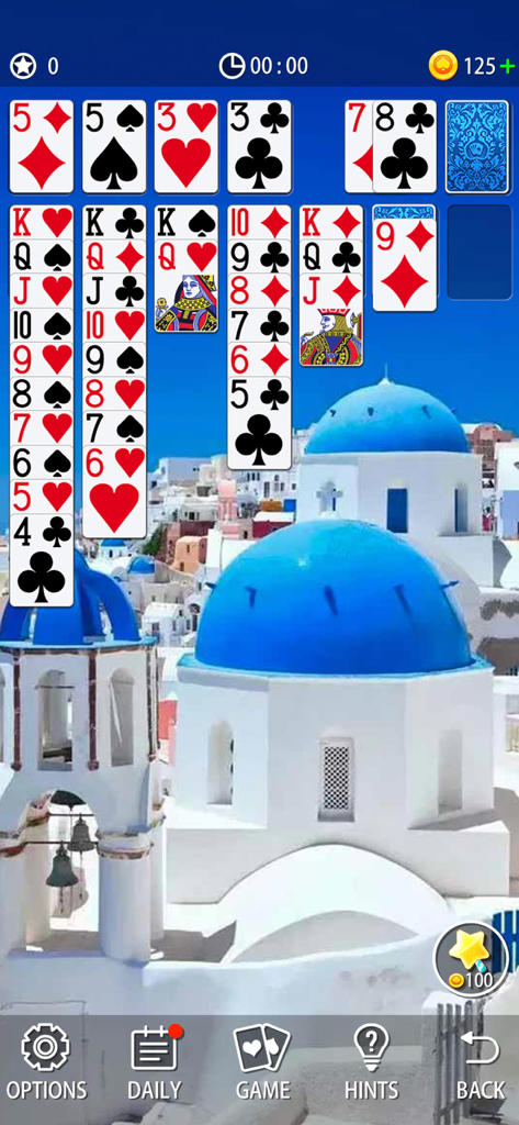 Classic Solitaire card game interface with a scenic blue-domed Santorini background.