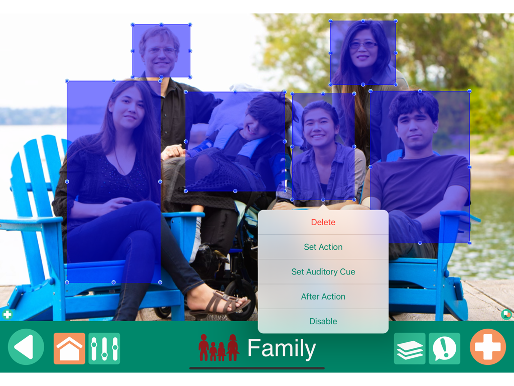 GoTalk NOW LITE interface showing a family photo scene with blue interactive hotspots for communication