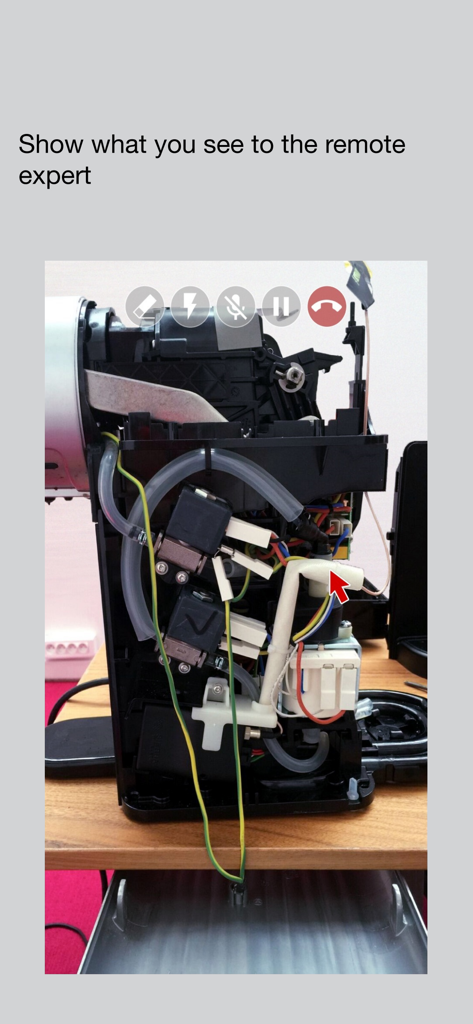 Capture d'écran d'un smartphone montrant l'application d'assistance visuelle utilisée pour obtenir l'aide d'un expert en réparation d'appareil électroménager, avec un pointeur rouge.
