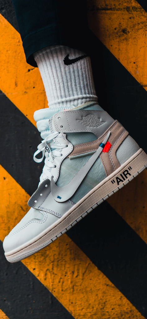 KicksOnFire: Release Dates - Zapatilla Off-White x Air Jordan 1 blanca sobre un fondo a rayas amarillas y negras.