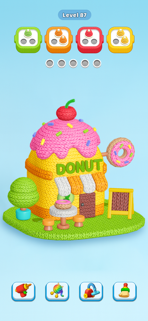 A 3D knitted donut shop being unraveled into color coded sorting boxes in a mobile puzzle game.