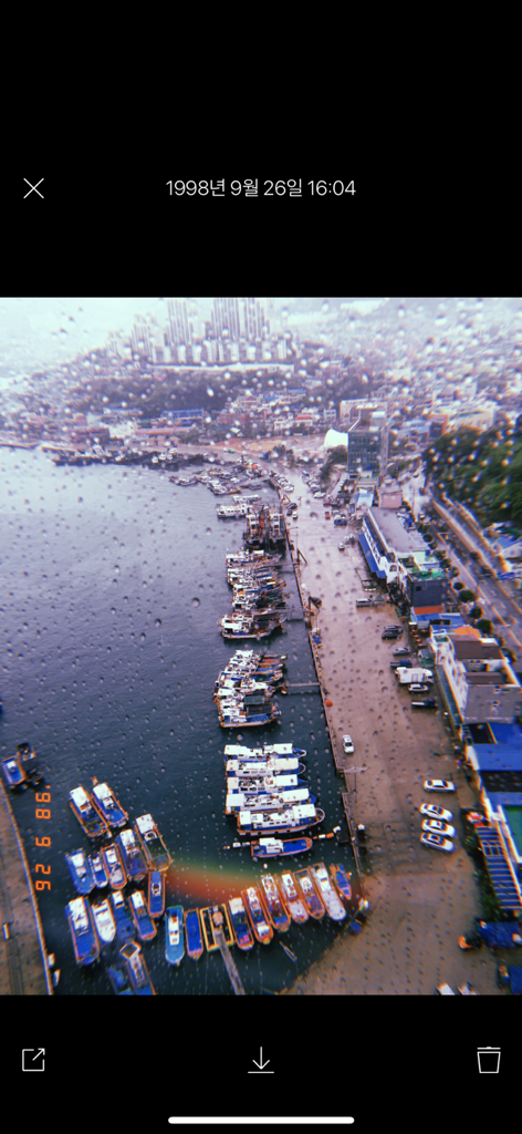 Foto estilo vintage de un puerto a través de una ventana lluviosa con un sello de fecha naranja de 1998 y efecto de fuga de luz