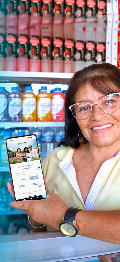 Banco Mundo Mujer - Uma mulher em sua loja segurando um telefone mostrando o aplicativo Banco Mundo Mujer.