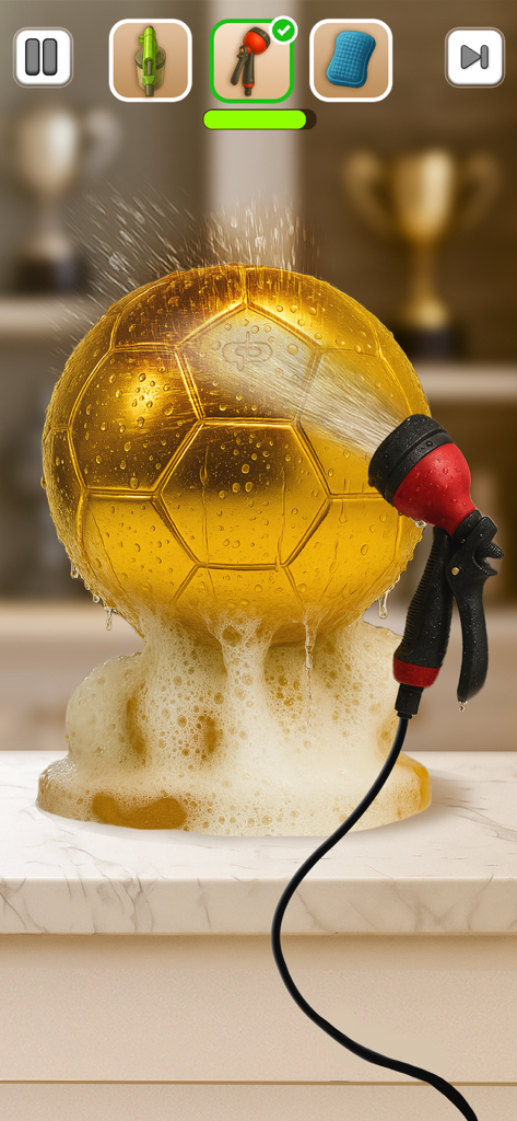 A golden soccer trophy being washed with a water nozzle and soapy suds.
