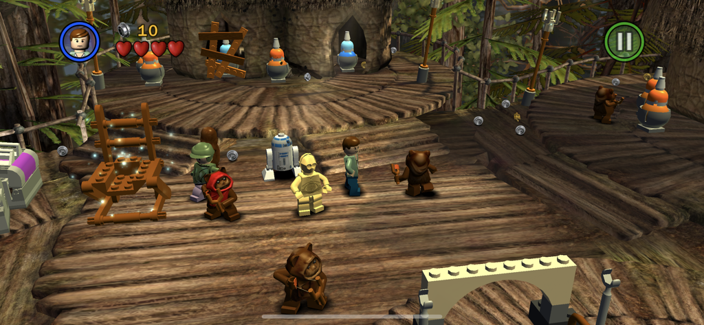 Screenshot di gameplay di LEGO Star Wars che mostra Luke Skywalker, C3PO, R2D2 ed Ewok in un villaggio nella foresta