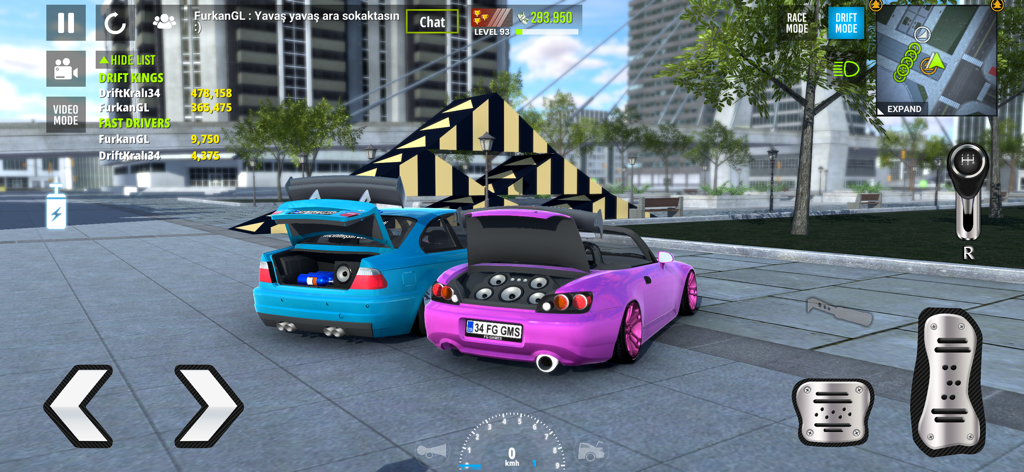 Dos coches deportivos personalizados mostrando sus sistemas de sonido en el maletero en un entorno de ciudad.