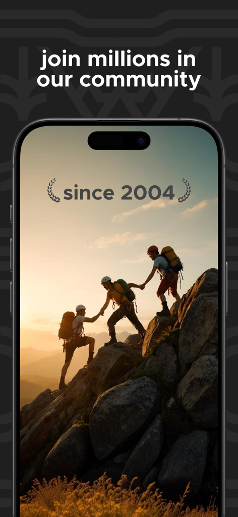 Three mountaineers helping each other reach a rocky summit at sunset