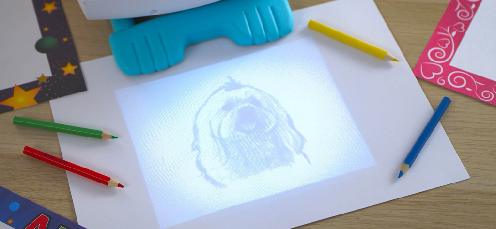 A smART sketcher projector projecting a dog sketch onto a piece of paper for tracing with colored pencils