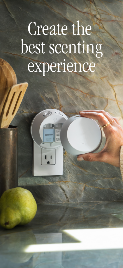 주방 벽 콘센트에 꽂힌 Pura 스마트 디퓨저에 향기 카트리지를 끼우는 손.