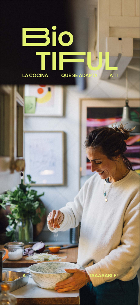 Biotiful App: tu cocina fácil - Woman smiling while seasoning a healthy meal in a bright kitchen with Biotiful App branding