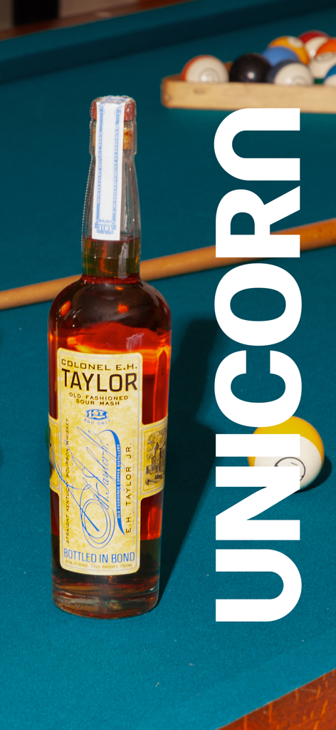 Una rara bottiglia di bourbon Colonel E.H. Taylor su un tavolo da biliardo che rappresenta il mercato di Unicorn Auctions.