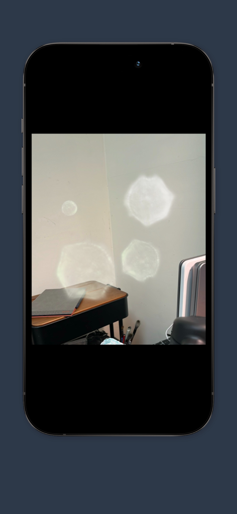 A smartphone screen showing the Ghost Detector app capturing white glowing orb anomalies in a room