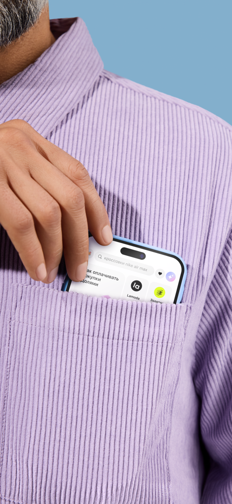 Dolyame - оплата покупок - Una mano metiendo un smartphone que muestra la interfaz de la aplicación Dolyame en el bolsillo de una camisa de pana morada.