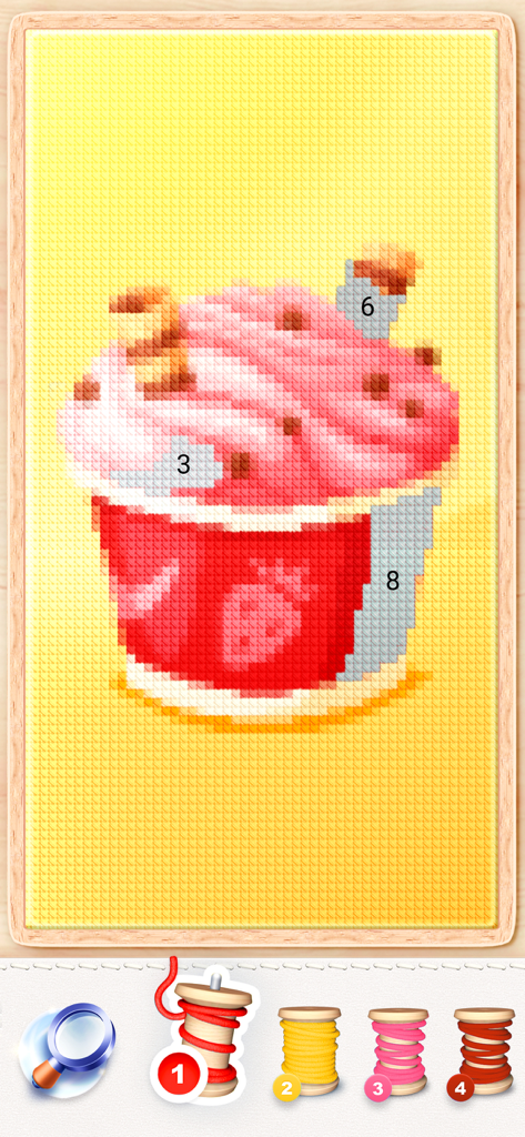 A digital cross stitch pattern of a pink cupcake being colored by numbers with thread spools at the bottom