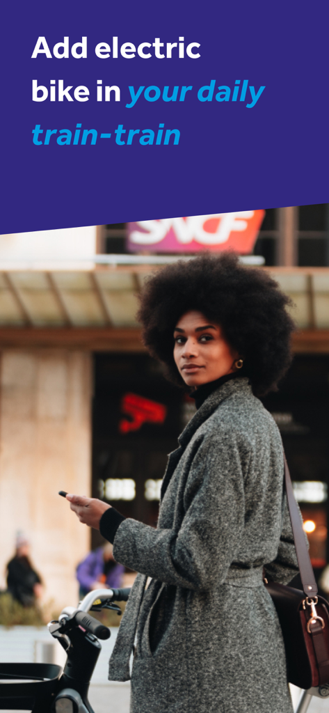 Vélo Modalis - Une femme avec un smartphone se tenant à côté d'un vélo électrique dans une gare