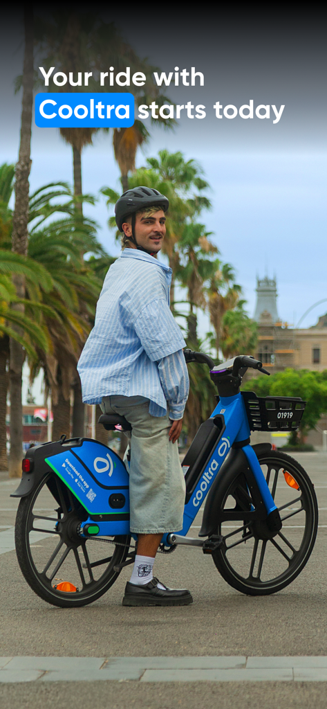 Young man wearing a helmet on a blue Cooltra e-bike in a city with palm trees