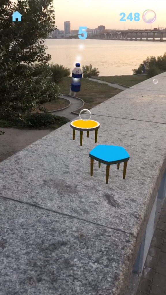 Gameplay de AR Bottle Flip montrant une bouteille virtuelle atterrissant sur des tables numériques placées sur une corniche en pierre à l'extérieur.