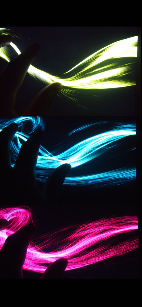 Triple A - Touch Visualizer - Une main créant des traînées lumineuses jaunes, bleues et roses sur un fond noir à l'aide de l'application Triple A