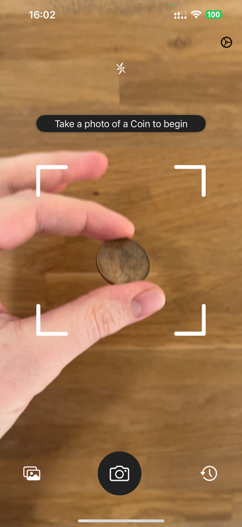Coin Scanner: Identify & Value - A hand holding a coin in front of a smartphone camera using the Coin Scanner app to identify its value.